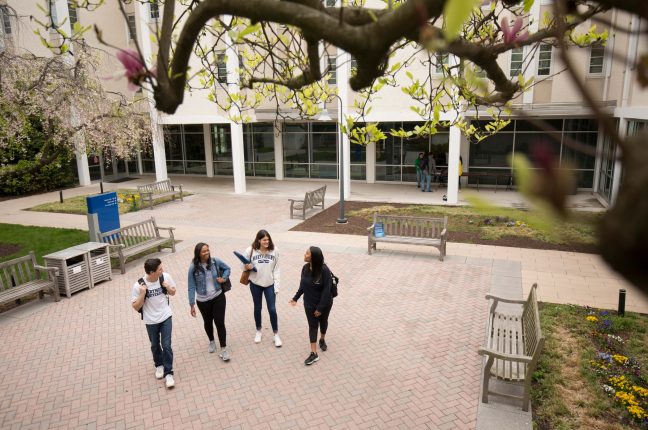 Students walk across a courtyard patio